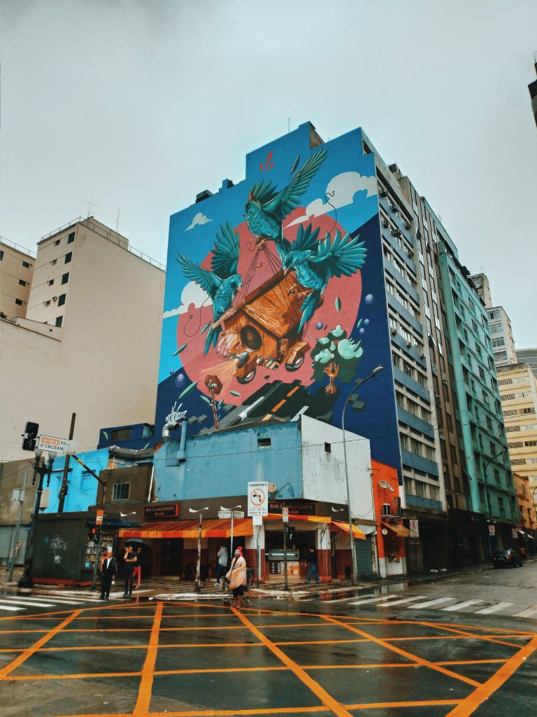 Grey sky covered with clouds above tall colorful multi storey construction decorated with image on side part