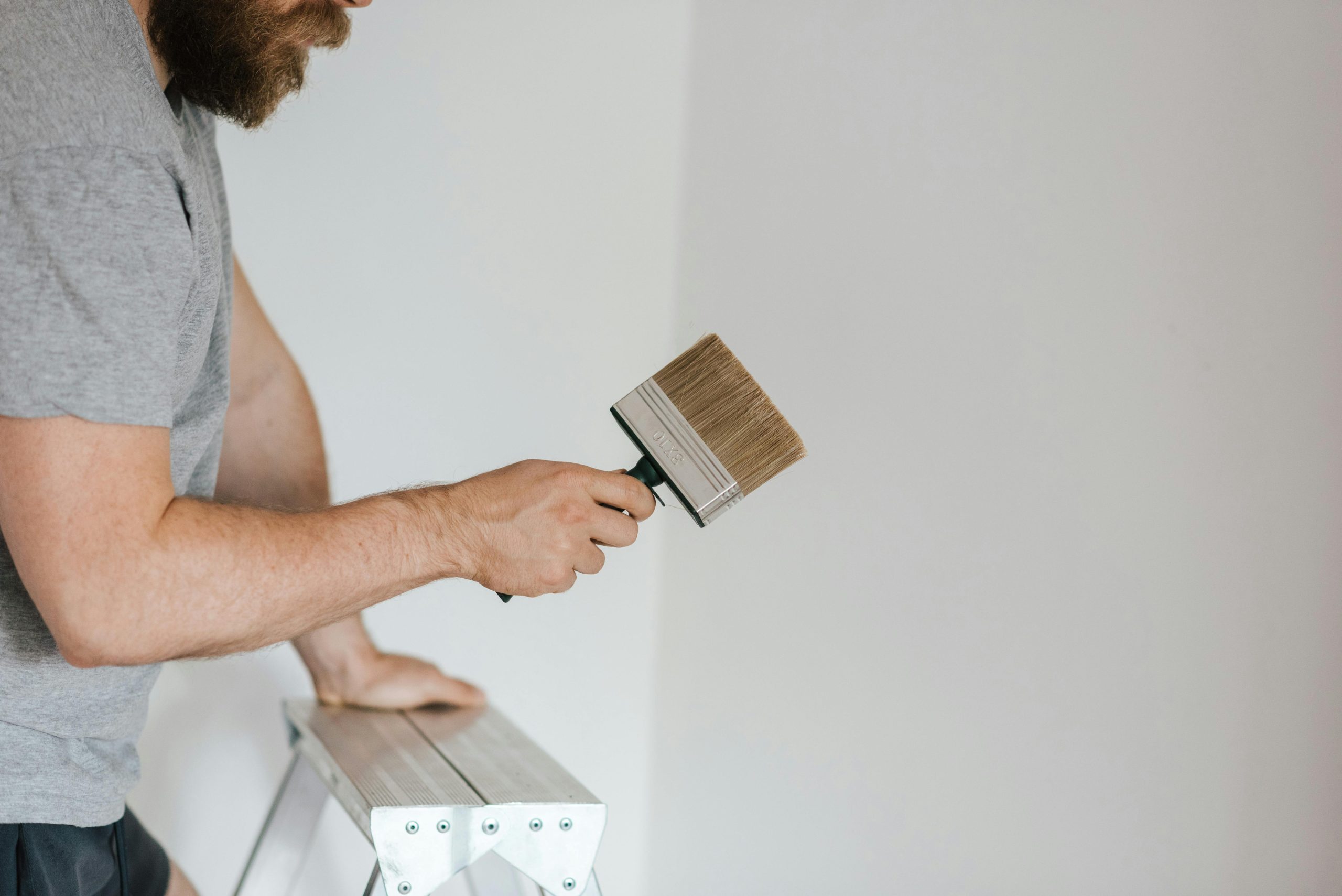 Bearded painter examining paintbrush in light room